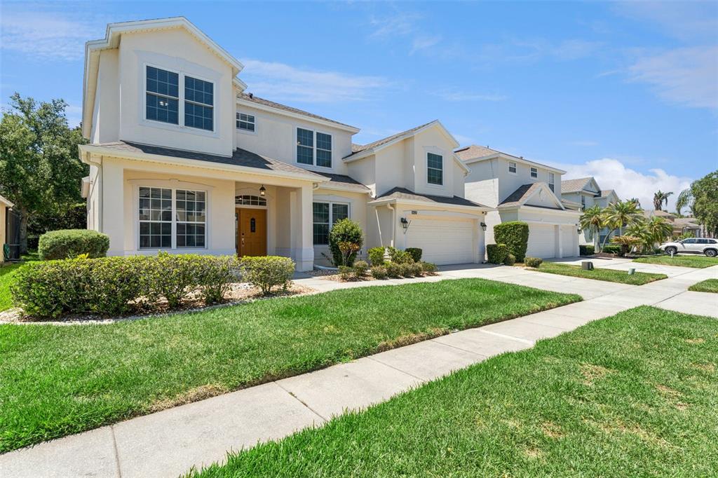 A two-story suburban house with a beige stucco exterior, a garage, and a front lawn — 10125 SANDY MARSH LANE, ORLANDO, FL