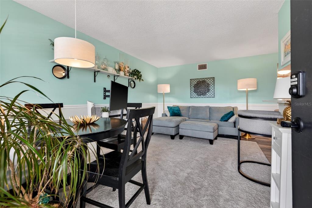 A living room features a grey sectional sofa, a white media console, and light blue walls — 4000 3RD STREET N UNIT 304, ST PETERSBURG, FL