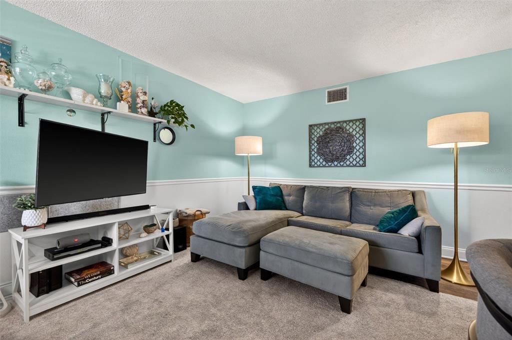 A living room and dining area feature light blue walls, wood flooring, and a sectional sofa — 4000 3RD STREET N UNIT 304, ST PETERSBURG, FL