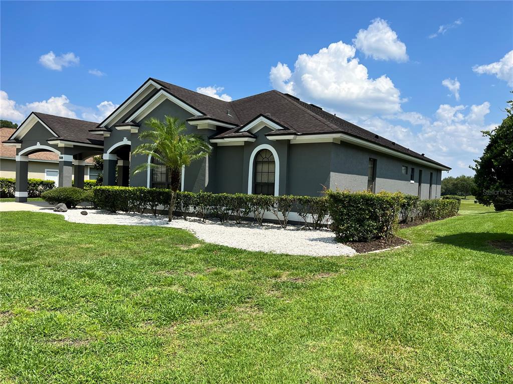 A gray single-story house with a dark shingled roof and white-trimmed arched windows — 508 LANARKSHIRE PLACE, APOPKA, FL