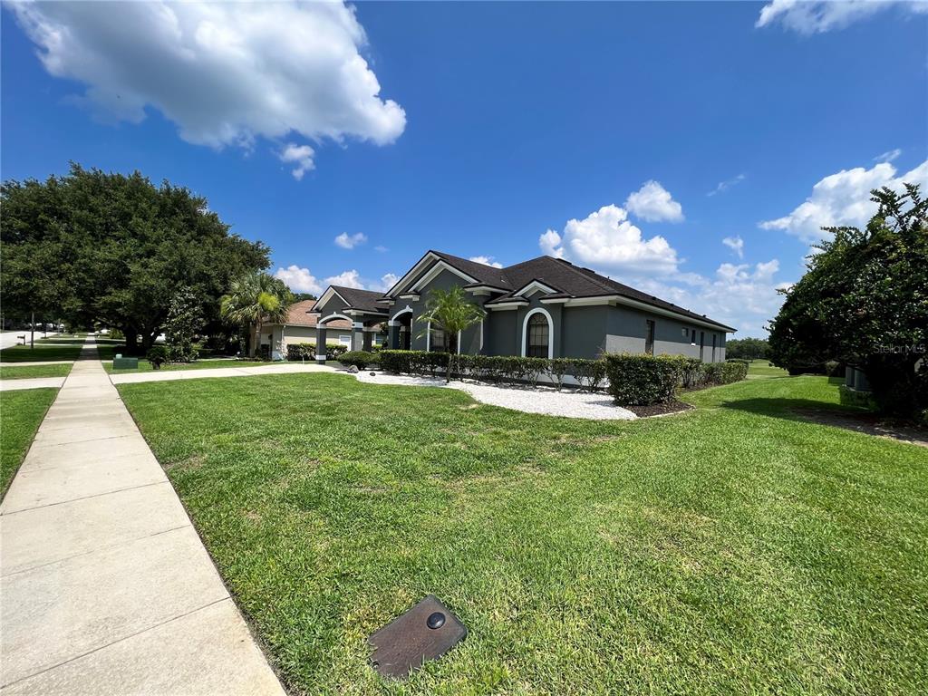 A gray single-story house with a dark roof sits on a grassy corner lot — 508 LANARKSHIRE PLACE, APOPKA, FL