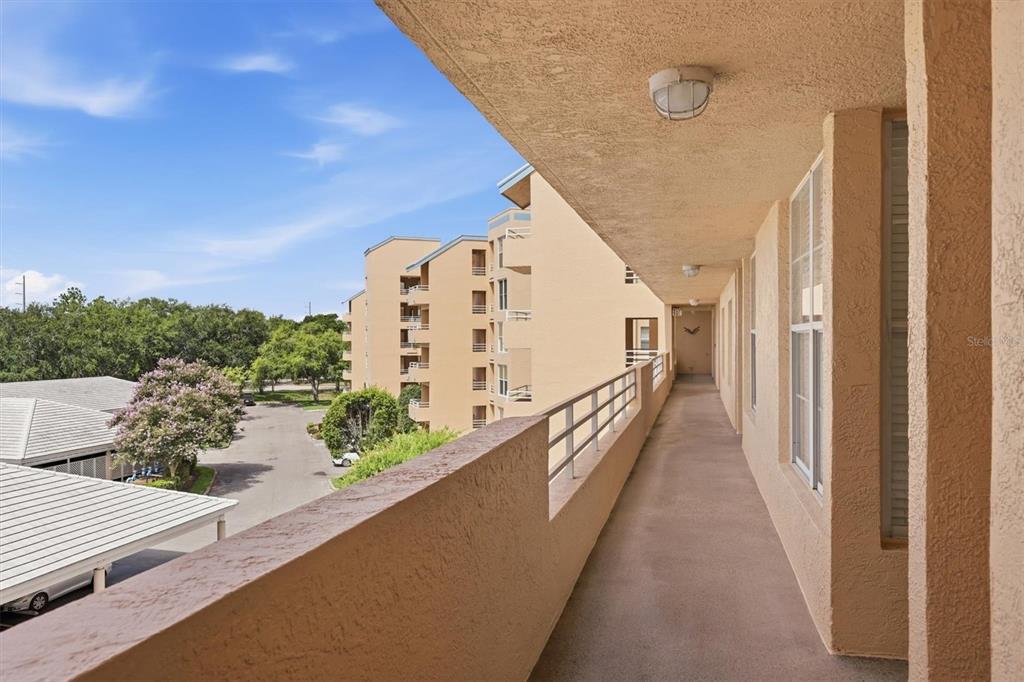An outdoor walkway with a concrete floor and metal railing overlooks a parking lot — 4550 PINEBROOK CIRCLE UNIT 403, BRADENTON, FL