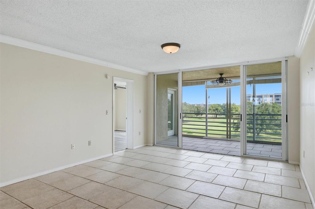 An empty room with tiled floors features a sliding glass door leading to a balcony — 4550 PINEBROOK CIRCLE UNIT 403, BRADENTON, FL
