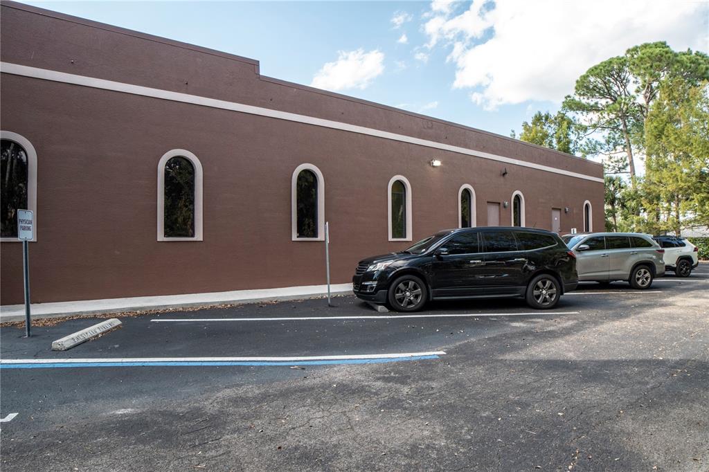 A brown building exterior features arched windows and a parking lot with several parked cars — 2484 CARING WAY UNIT F, PORT CHARLOTTE, FL