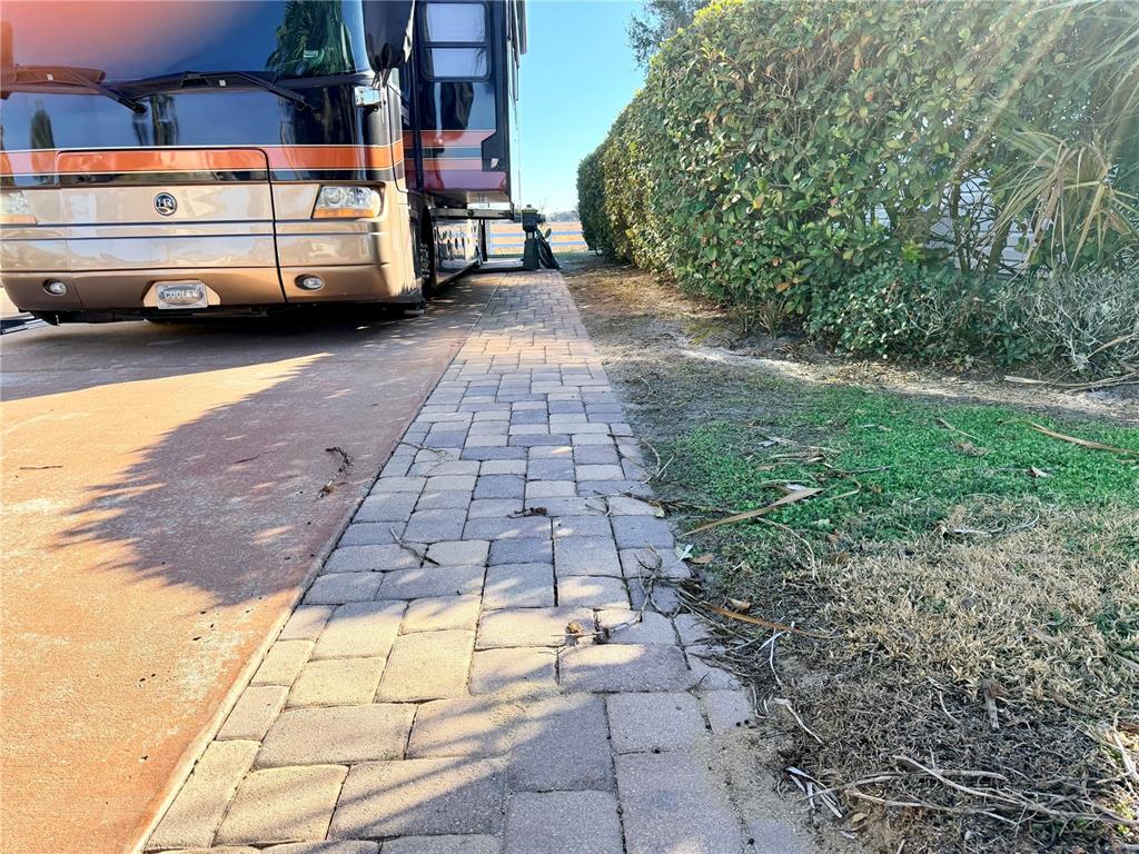 A large recreational vehicle is parked on a paved driveway next to a hedge — 4805 SE 94TH AVENUE, WEBSTER, FL