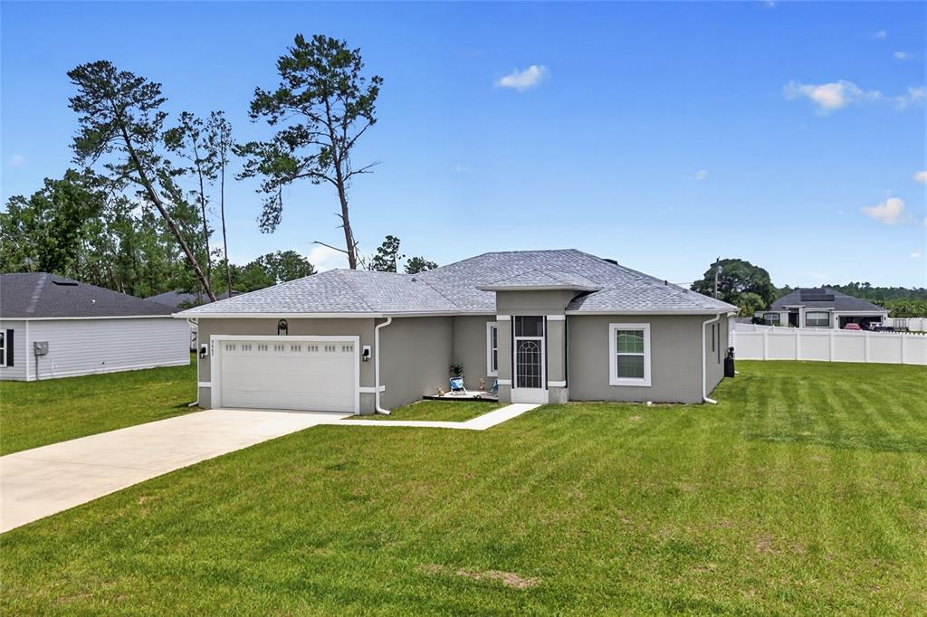 A single-story gray house with a two-car garage and a white vinyl fence — 3557 SW 128TH PLACE, OCALA, FL