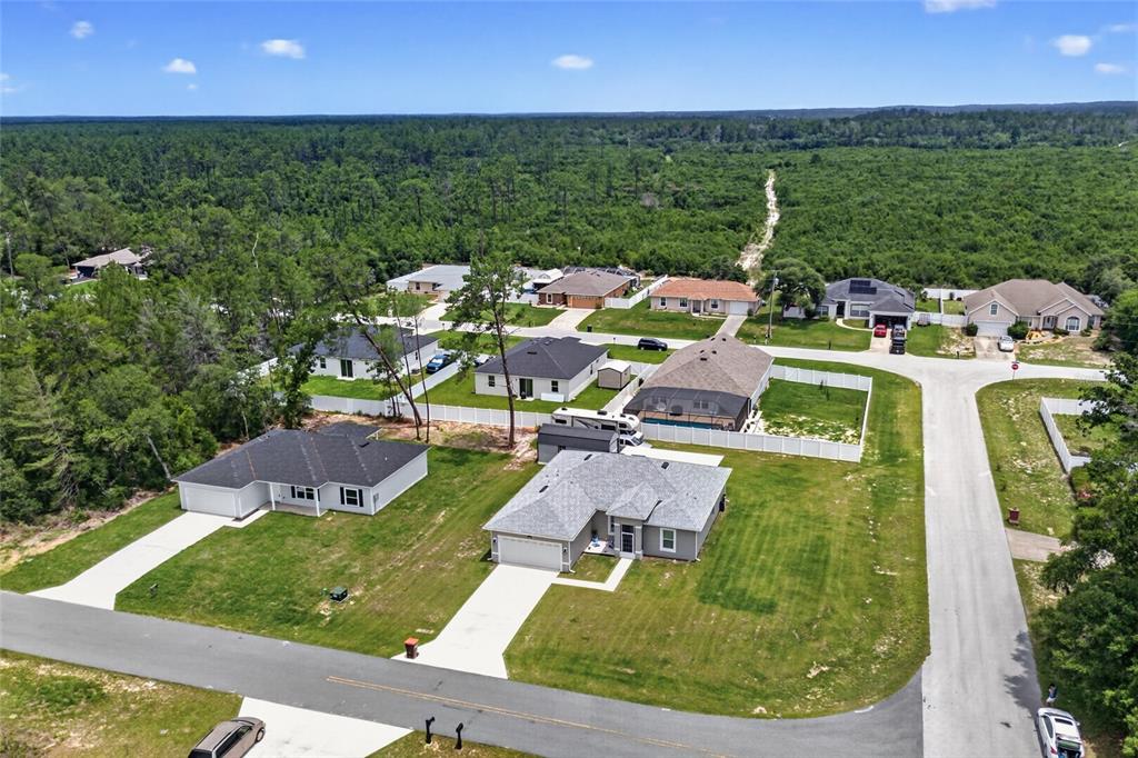 An aerial view shows several suburban houses surrounded by a large forest — 3557 SW 128TH PLACE, OCALA, FL
