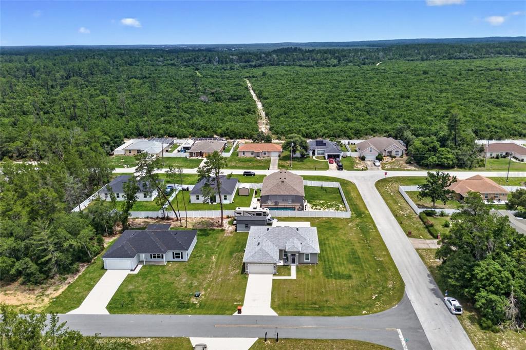 An aerial view shows several suburban houses surrounded by a large area of dense forest — 3557 SW 128TH PLACE, OCALA, FL
