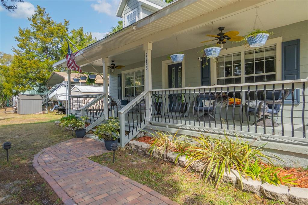 A light green house features a covered front porch with a brick walkway and landscaping — 2283 S TODD POINT, HOMOSASSA, FL