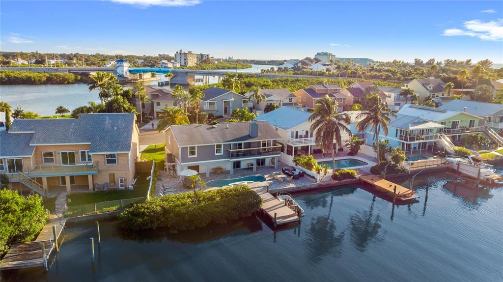An aerial view of waterfront houses with private docks, swimming pools, and a nearby bridge — 328 6TH AVENUE, INDIAN ROCKS BEACH, FL