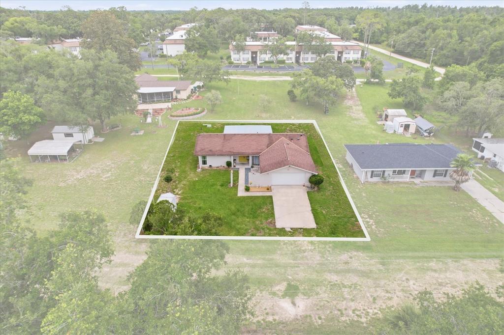 An aerial view shows a single-story house with a brown roof and a concrete driveway — 2507 BLUEGRASS STREET, INVERNESS, FL