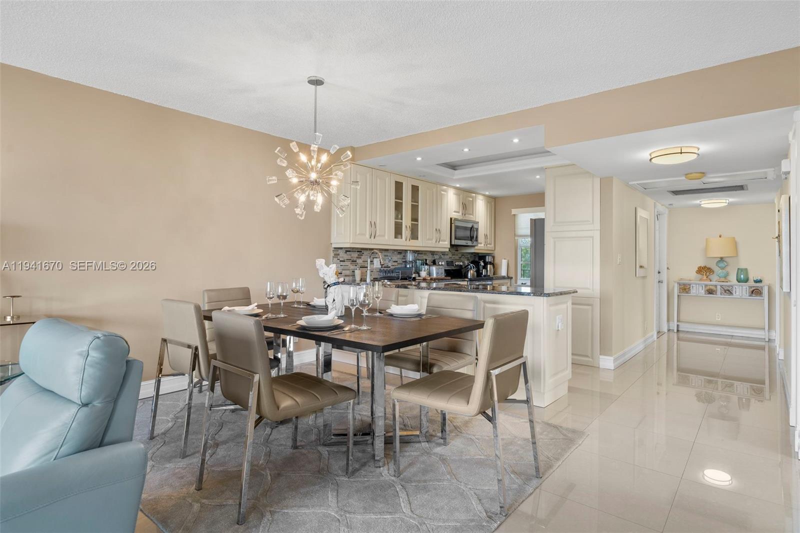 A dining area with a modern chandelier sits adjacent to an open kitchen with cabinetry — 4030 W Palm Aire Dr # 408, Pompano Beach FL 33069, POMPANO BEACH, FL