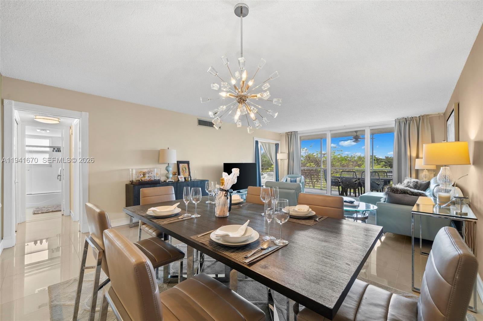 A dining area with a dark wood table, modern chandelier, and adjacent living room space — 4030 W Palm Aire Dr # 408, Pompano Beach FL 33069, POMPANO BEACH, FL