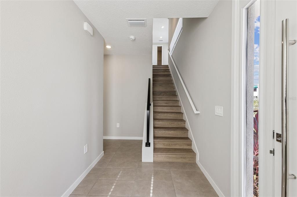 A tiled entryway features a staircase with wood-look steps and a black metal handrail — 544 N BUMBY AVENUE UNIT 5, ORLANDO, FL