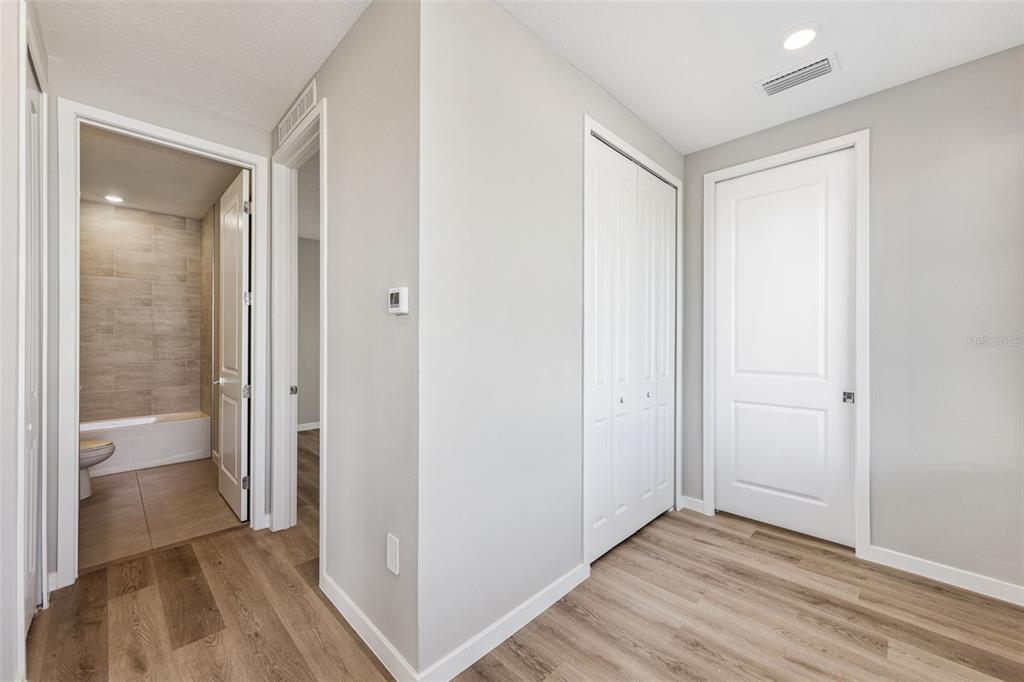 A hallway with wood-look flooring leads to a bathroom and two closed white doors — 544 N BUMBY AVENUE UNIT 5, ORLANDO, FL