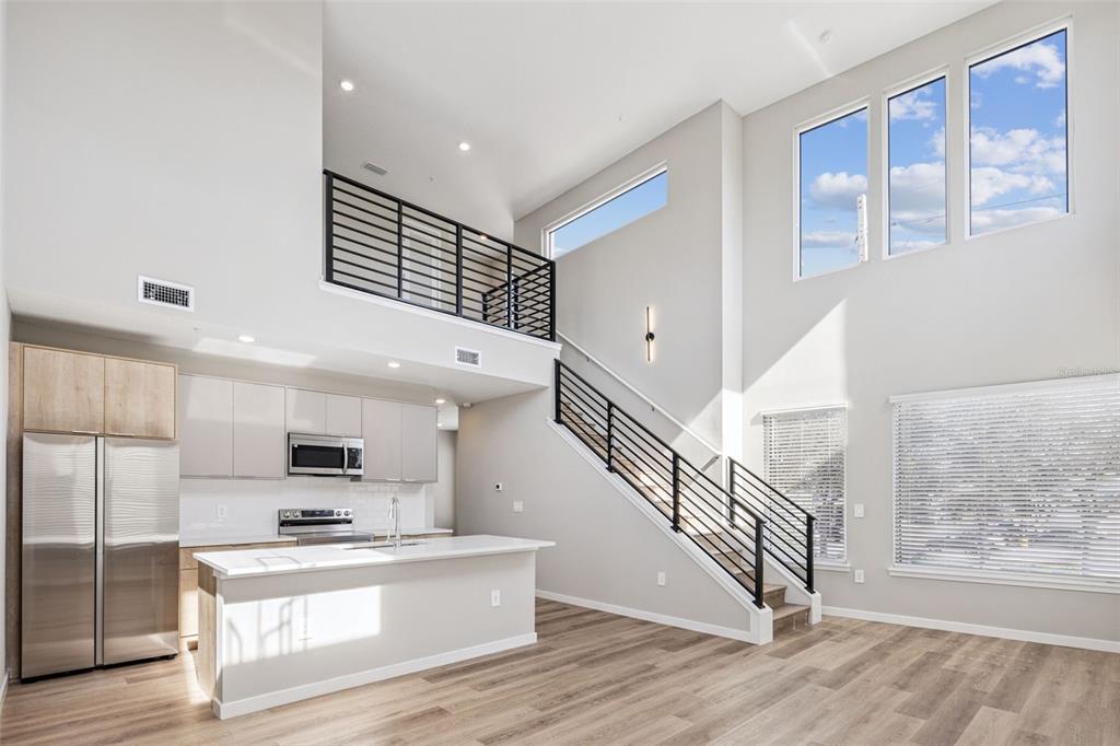 A modern kitchen and living area feature high ceilings, a loft, and a staircase — 544 N BUMBY AVENUE UNIT 5, ORLANDO, FL