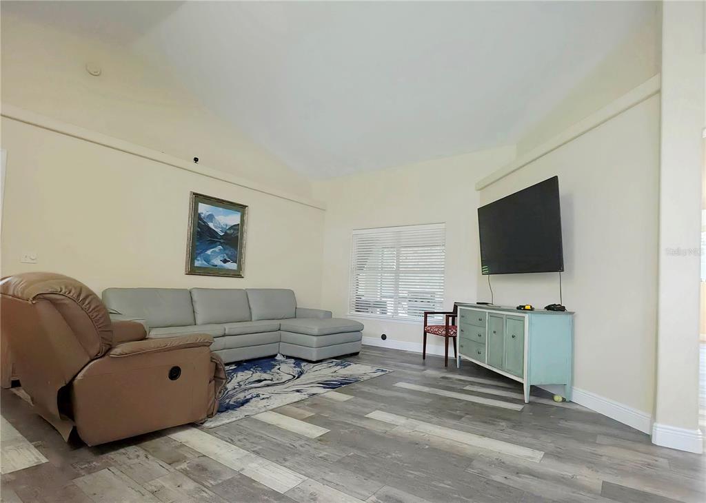 A living room features a gray sectional sofa, a brown recliner, and a wall-mounted television — 13518 PALO COURT, CLERMONT, FL