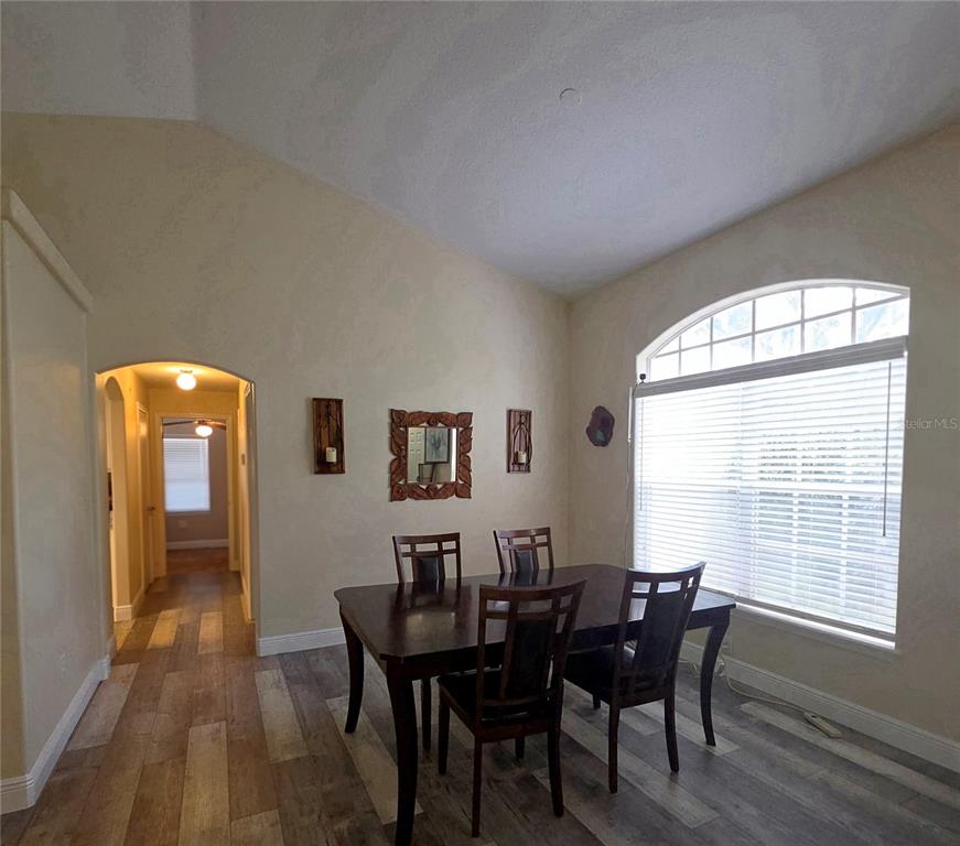 A dining room with a vaulted ceiling, wood-look flooring, and a large arched window — 13518 PALO COURT, CLERMONT, FL