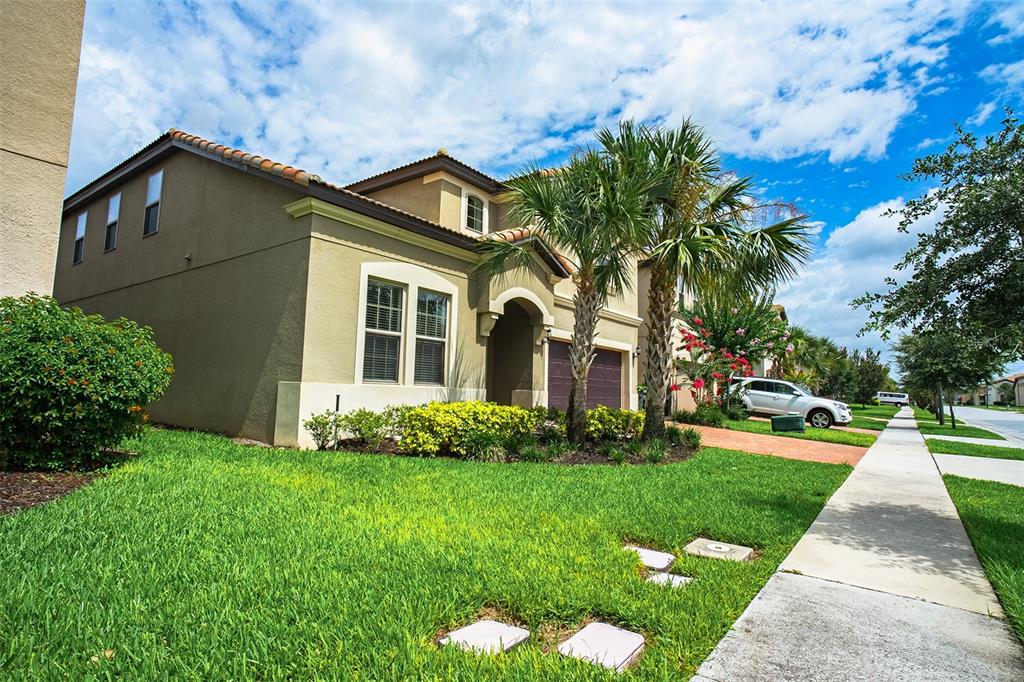 A two-story tan stucco house with a tile roof, palm trees, and a front lawn — 1682 LIMA AVENUE, KISSIMMEE, FL