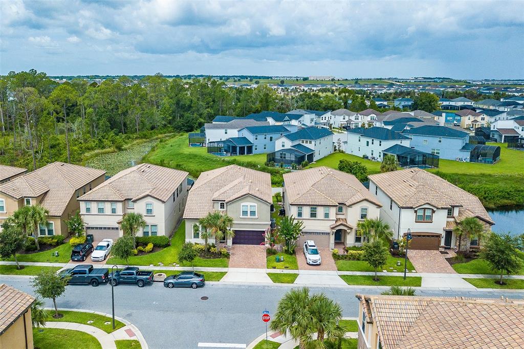 An aerial view shows a suburban neighborhood with several two-story houses and a stop sign — 1682 LIMA AVENUE, KISSIMMEE, FL