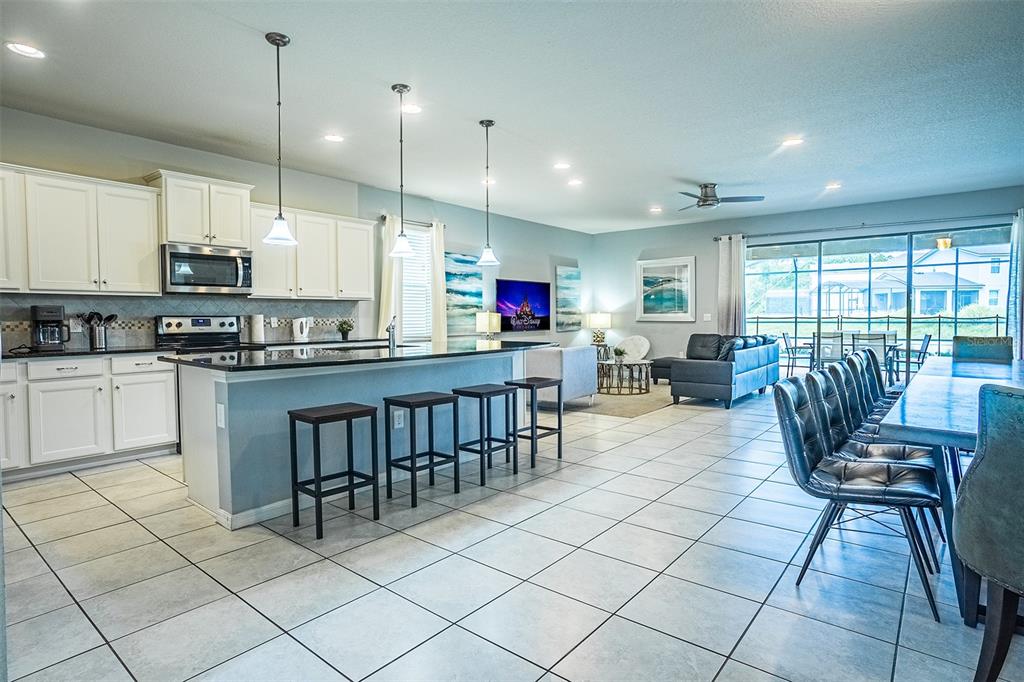 An open-concept kitchen and living area features white cabinetry, a kitchen island, and tile flooring — 1682 LIMA AVENUE, KISSIMMEE, FL