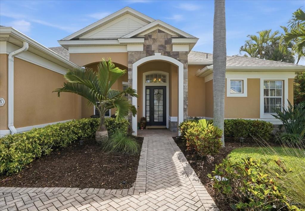 A single-story house with a stone-accented entryway, a brick walkway, and a palm tree — 8843 17TH AVENUE CIRCLE NW, BRADENTON, FL