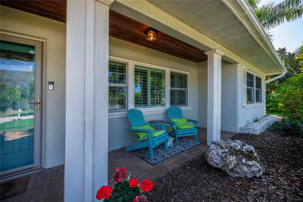 A covered front porch features two turquoise Adirondack chairs on a patterned rug — 809 NOKOMIS AVENUE S, VENICE, FL