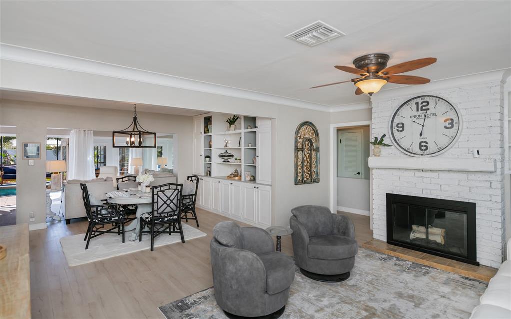 A living room and dining area feature a white brick fireplace, gray armchairs, and built-in shelving — 809 NOKOMIS AVENUE S, VENICE, FL