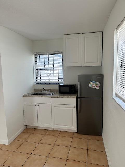 A small kitchen features white cabinets, a stainless steel sink, a microwave, and a refrigerator — 807 Phippen Waiters Road # 2, Dania Beach FL 33004, DANIA BEACH, FL