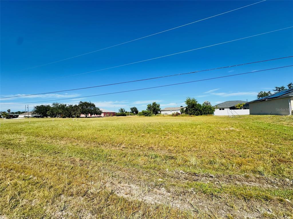 A large, flat, grassy vacant lot under a clear blue sky — 2053 NW 3RD STREET, CAPE CORAL, FL