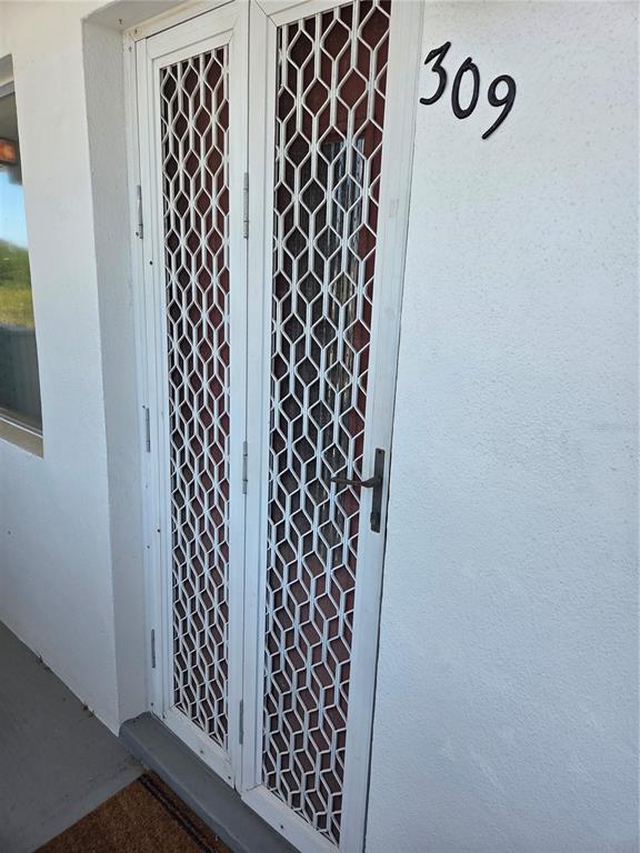 A white exterior door with a diamond-pattern security gate and the number 309 above it — 11225 82ND AVENUE UNIT 309, SEMINOLE, FL