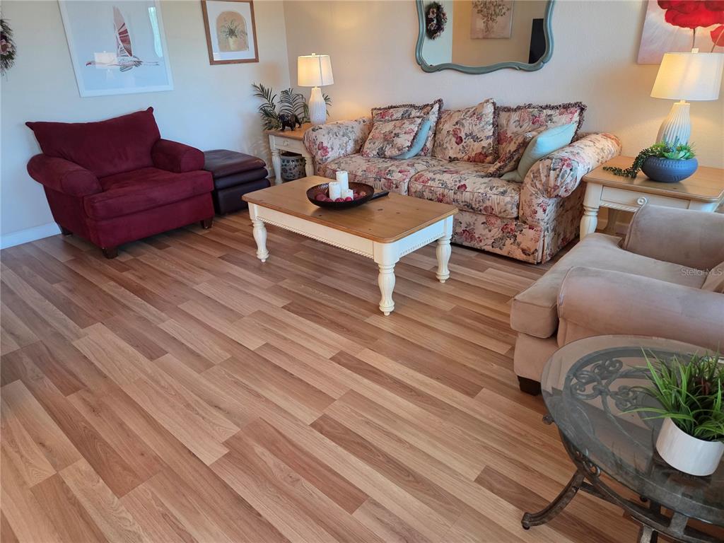 A living room features floral and solid-colored furniture, a wooden coffee table, and wood flooring — 11225 82ND AVENUE UNIT 309, SEMINOLE, FL