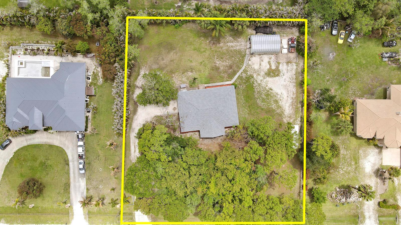 An aerial view shows a house with a gray roof on a large, wooded lot — 16296 81st Lane N, FL 33470, FL
