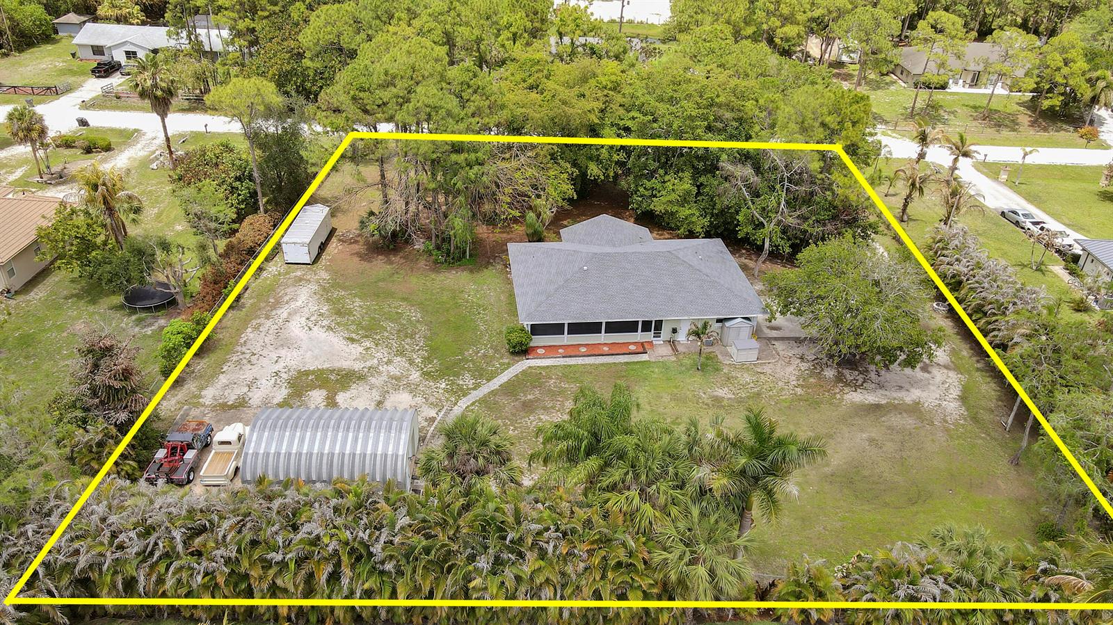 An aerial view shows a house with a metal shed and trailer on a wooded lot — 16296 81st Lane N, FL 33470, FL