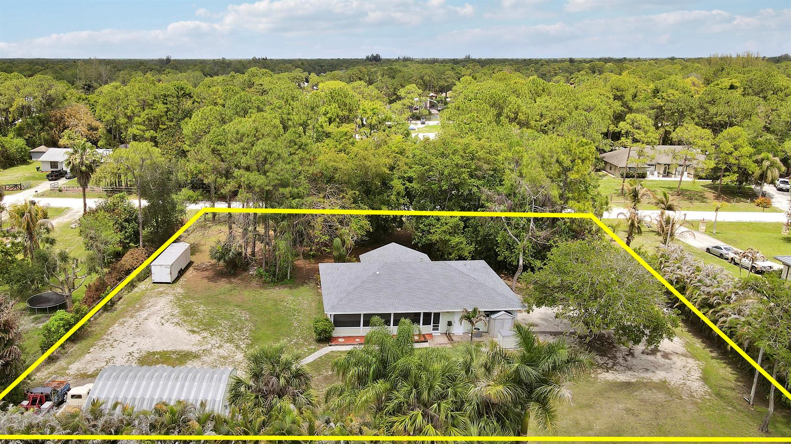 An aerial view of a single-story house with a screened porch on a wooded lot — 16296 81st Lane N, FL 33470, FL