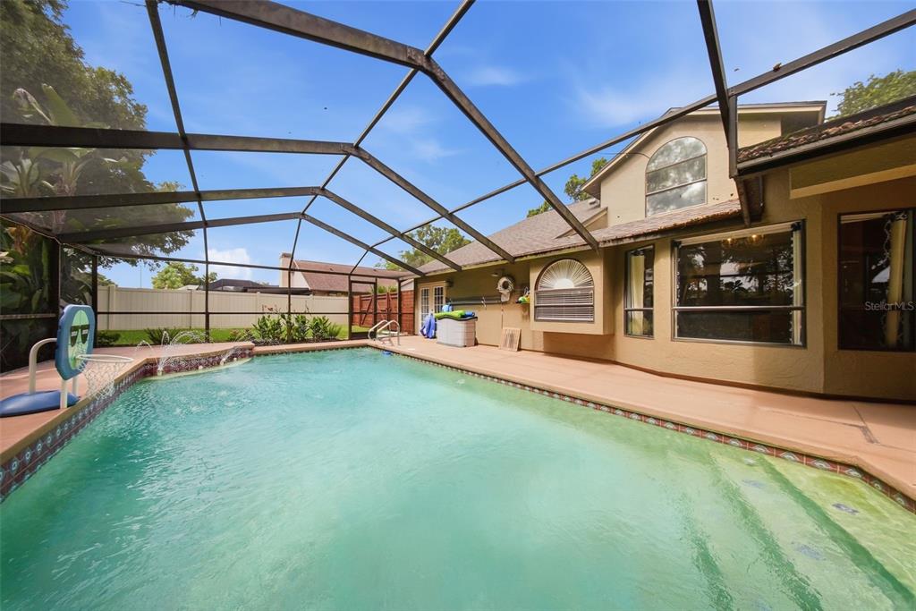 A swimming pool with a screen enclosure sits in the backyard of a two-story home — 2704 BUCKHORN OAKS DRIVE, VALRICO, FL