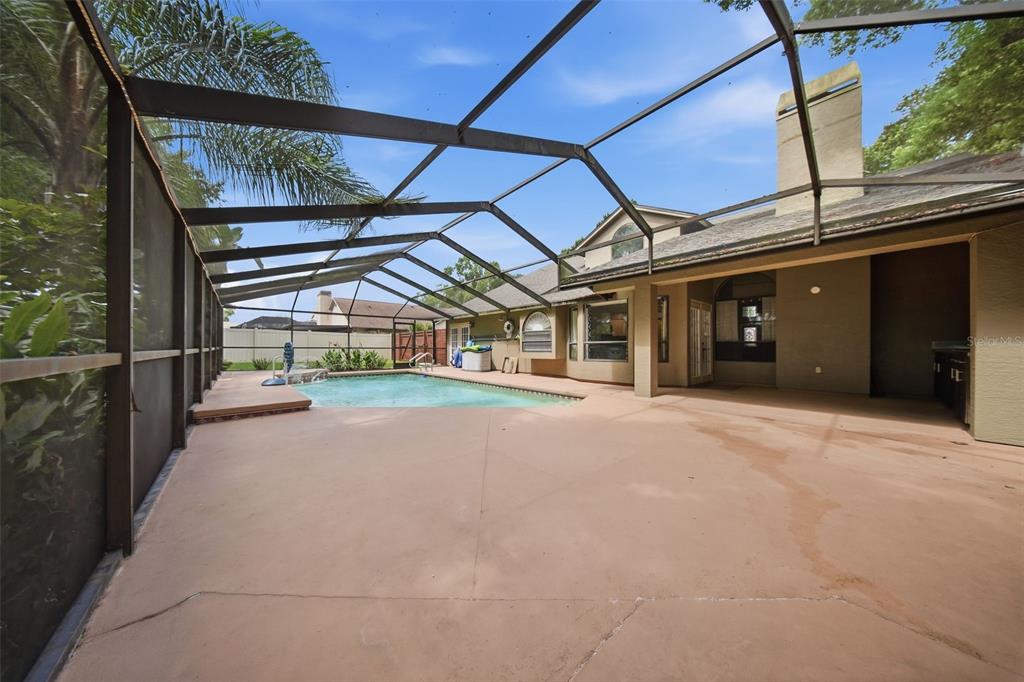 A screened-in patio features a swimming pool and a concrete deck beside a house — 2704 BUCKHORN OAKS DRIVE, VALRICO, FL