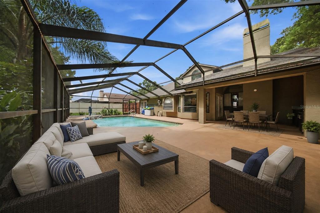 A screened-in patio features a swimming pool, outdoor seating area, and dining space — 2704 BUCKHORN OAKS DRIVE, VALRICO, FL