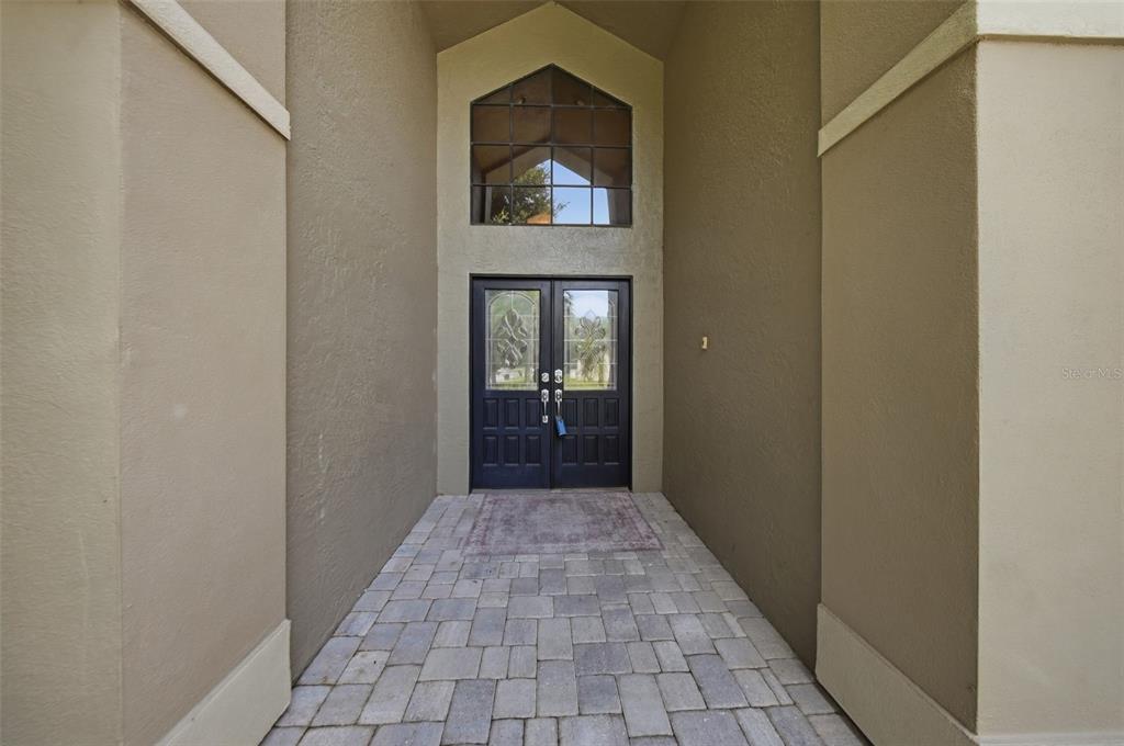 A paved entryway leads to a dark double front door with a large arched window above — 2704 BUCKHORN OAKS DRIVE, VALRICO, FL