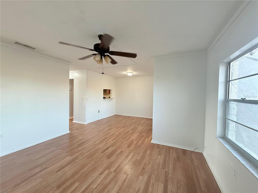 An empty room with wood-look flooring, white walls, a ceiling fan, and a window — 108 BOOTH LANE, KISSIMMEE, FL
