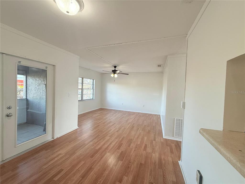 An interior view of a living room with wood-look flooring, white walls, and a ceiling fan — 108 BOOTH LANE, KISSIMMEE, FL