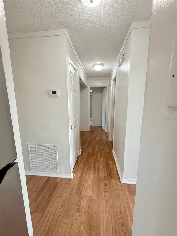 A hallway with wood-look flooring leads to a doorway at the end of the corridor — 108 BOOTH LANE, KISSIMMEE, FL