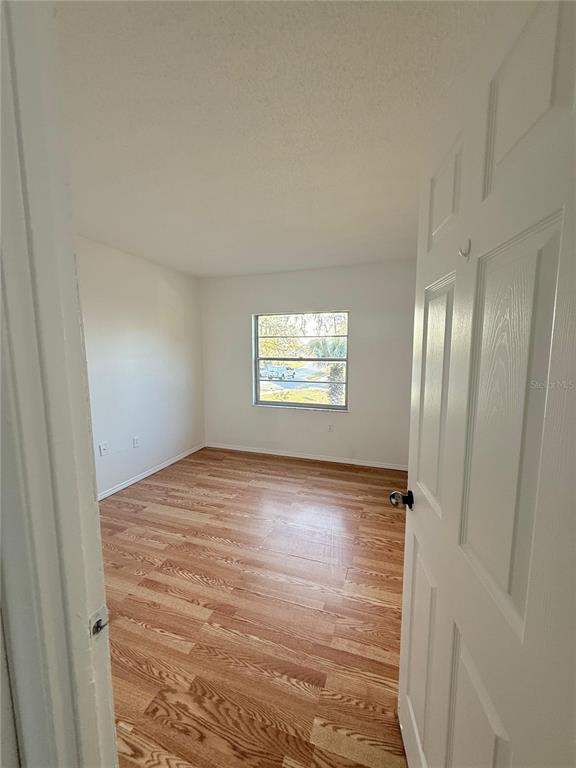 An empty bedroom features light wood-look flooring, white walls, and a single window — 108 BOOTH LANE, KISSIMMEE, FL
