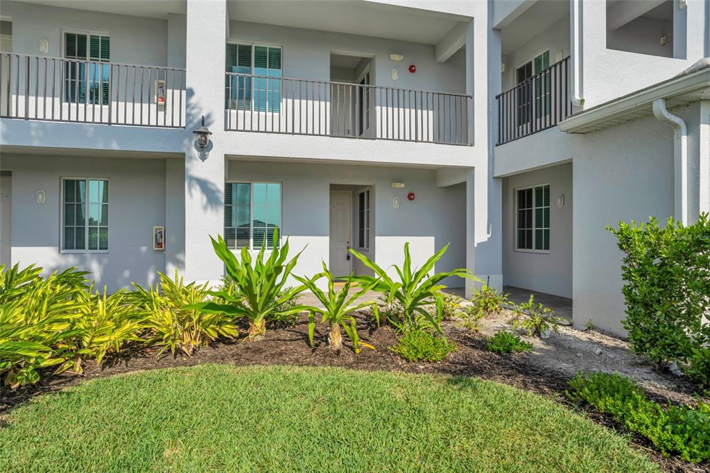 A two-story apartment building exterior features white stucco walls, metal railings, and landscaped garden beds — 14041 HERITAGE LANDING BOULEVARD UNIT 616, PUNTA GORDA, FL