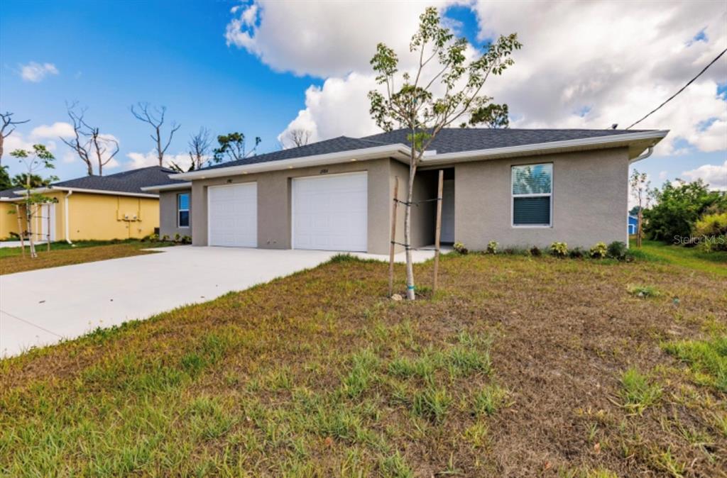 A single-story duplex with two white garage doors and a gray stucco exterior — 11982-11984 TETZEL AVENUE, PORT CHARLOTTE, FL