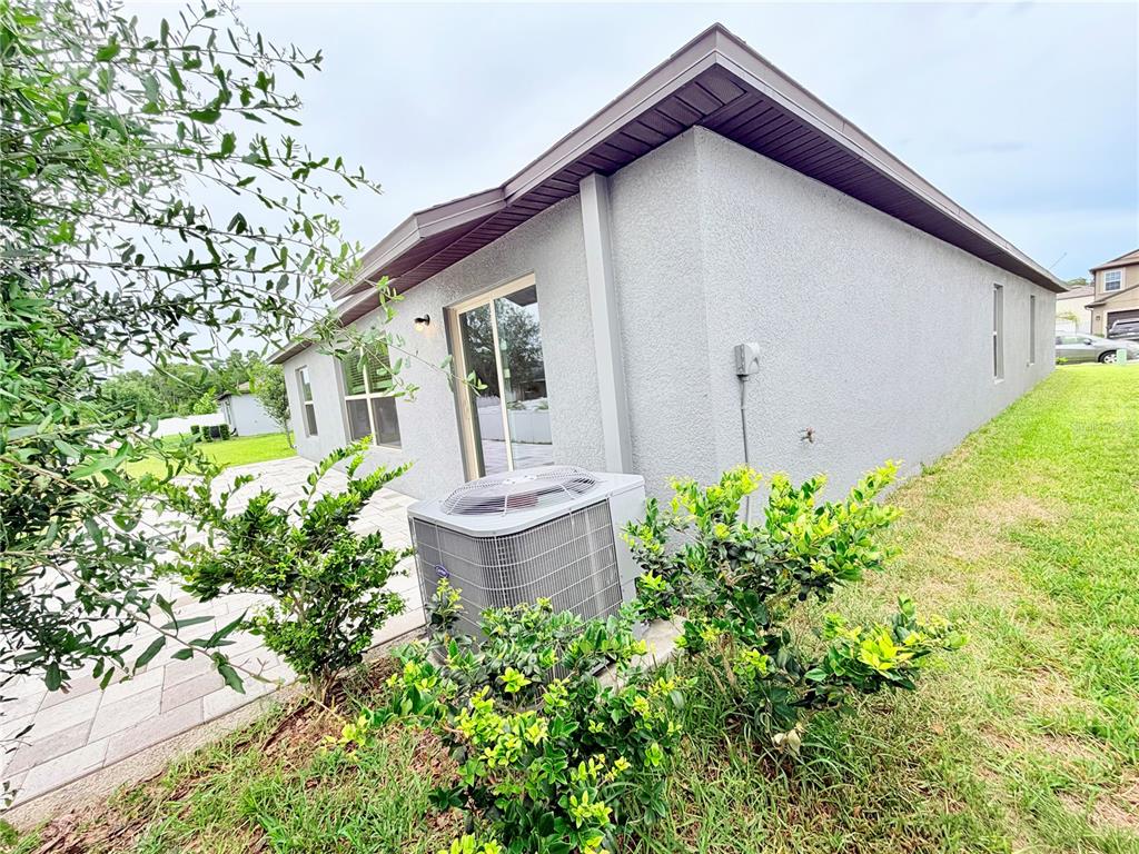 The exterior of a gray stucco house features a sliding glass door and an air conditioner — 184 ARGYLL DRIVE, SPRING HILL, FL
