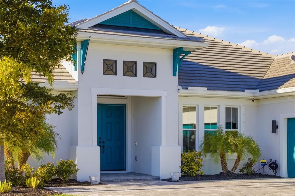 The exterior of a white house features a teal front door and matching decorative accents — 4677 ANTRIM DRIVE, SARASOTA, FL