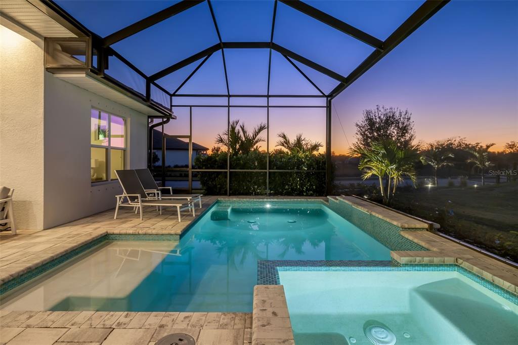 A screened-in patio features a swimming pool, a spa, and two lounge chairs at sunset — 4677 ANTRIM DRIVE, SARASOTA, FL