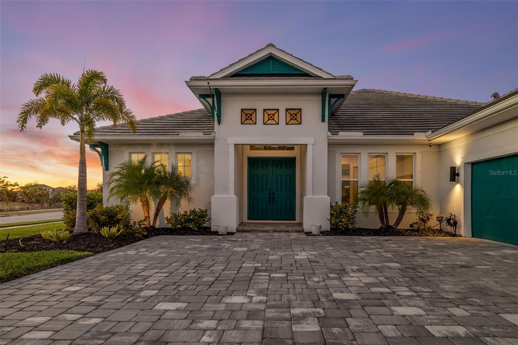 A single-story house with a teal front door, a paver driveway, and a palm tree — 4677 ANTRIM DRIVE, SARASOTA, FL
