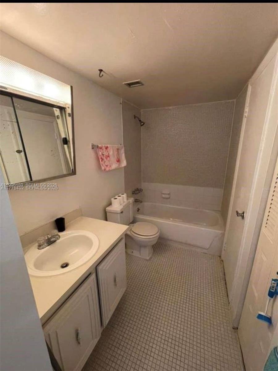 A bathroom features a white vanity, a toilet, and a shower-tub combination with tiled walls — 496 NW 165th St Rd # 611, Miami FL 33169, MIAMI, FL